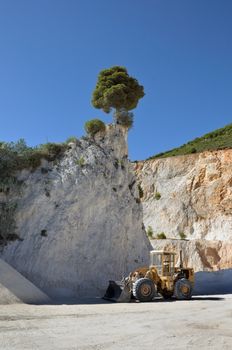 Bulldozer at quarry site digging into the mountain.