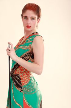 Young girl in colorful dress with a cue stick in hand