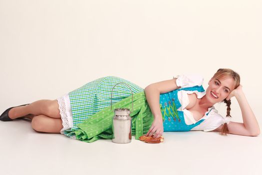 Bavarian girl lying on the floor laughing and playing with milk jug and food
