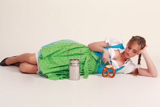 Bavarian girl is bored on the floor and playing with a milk jug and food