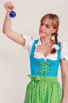 Bavarian girl in a dirndl, a blue Christmas tree ball in hand