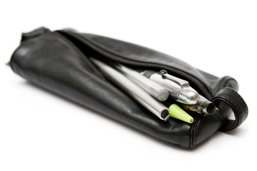 Writing utensils in a black leather pouch. Isolated on a white background.