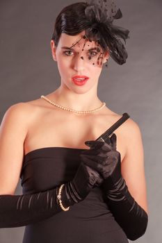 Elegant woman in black dress with gun and bow in her hair