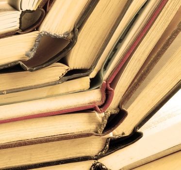 old dusty opened books stack on table, sepia toned