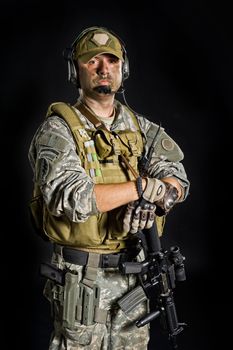 Soldier of USA army posing with a gun on a black background