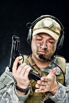 Soldier of USA army posing with a gun on a black background