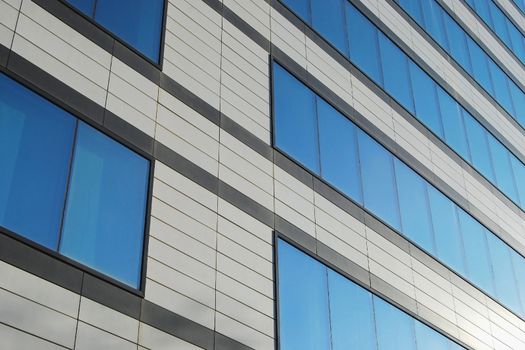Modern office building wall with blue glass windows close-up