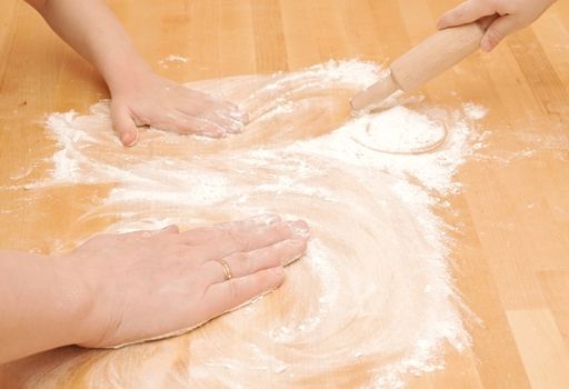 A child is helping mom to knead the dough for baking 