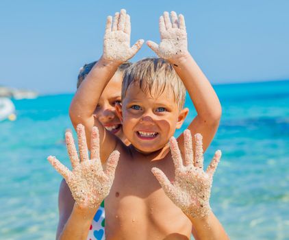 Close-up view of hands by the girl and boy on the sand beach.