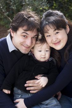 Multi ethnical family with Mother father and child looking at camera. Positive feeling, real people