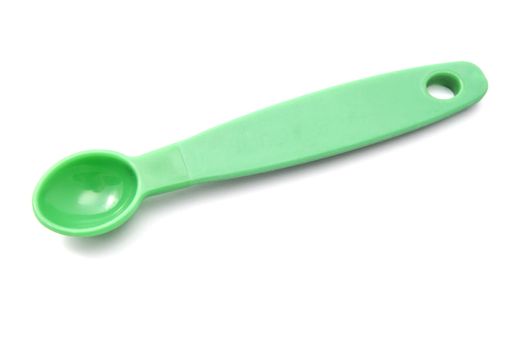 Green measuring spoon closeup on white background 