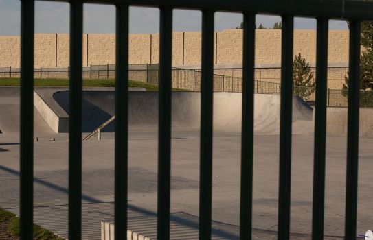 looking at deserted skate park through black fence