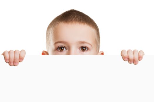 Little scared or worried child boy holding blank white sign or placard hiding face