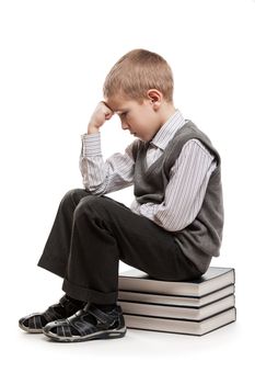 Puzzled or perplexed thinker child boy sitting on education reading books stack