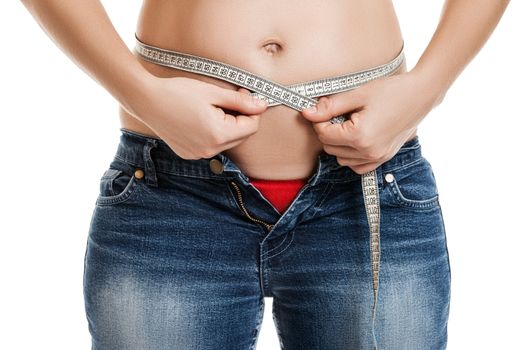 Overweight woman wearing jeans measuring her fat body belly paunch