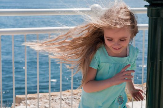 Little girl with long hair near blue sea
