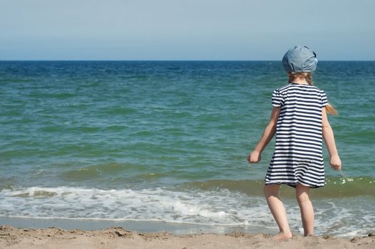 Girlin striped dress and denim hat and the sea