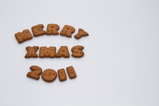 Merry Xmas 2011 wording from brown biscuits at left of the frame on white background  in landscape orientation