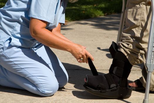 Female nurse adjusts strap on patient's ankle brace.