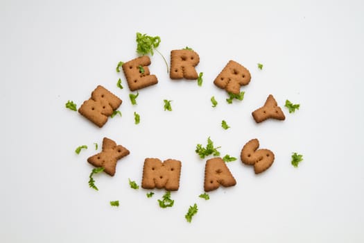 Merry Xmas wording from brown biscuits with green leaves on white background in landscape orientation