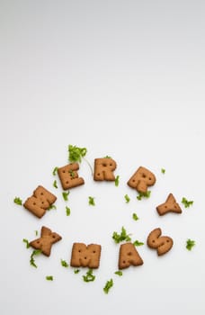 Merry Xmas wording from brown biscuits with green leaves on white background in portrait orientation