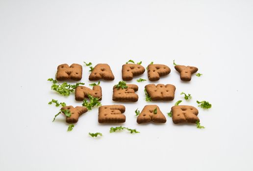 Happy New Year greeting words made by brown biscuits with green leaves on white surface in landscape orientation for background use slanting view