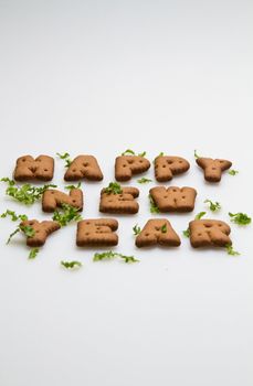 Happy New Year greeting words made by brown biscuits with green leaves on white surface in portrait orientation for background use slanting view