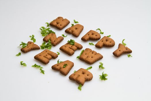 angled view of Happy New Year greeting words made by brown biscuits with green leaves on white surface in landscape orientation for background use