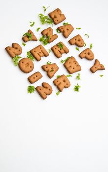 Angled view of Happy New Year greeting words made by brown biscuits with green leaves and copy space on upper center of white surface in portrait orientation for background use