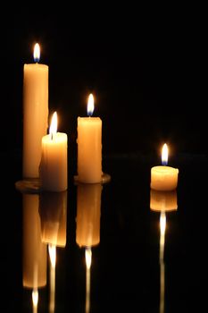 Set of lighting candles in a row on dark background with reverberation