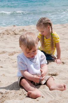 Two child sitting and playing on the beach