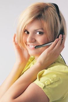 The young and beautiful girl from a support service with ear-phones and a microphone on a head