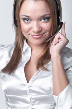 The young and beautiful girl from a support service with ear-phones and a microphone on a head