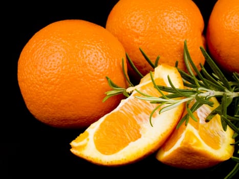 Oranges and fresh rosemary on black background