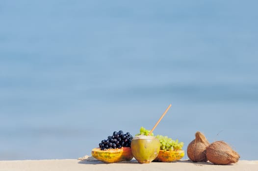 Papaya, coconut, nut and grapes on the sandy beach