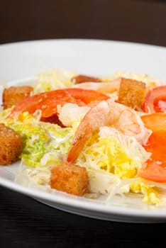 Salad of tiger shrimps, lettuce, chinese cabbage, tomato, garlic rusk, parmesan cheese and sauce