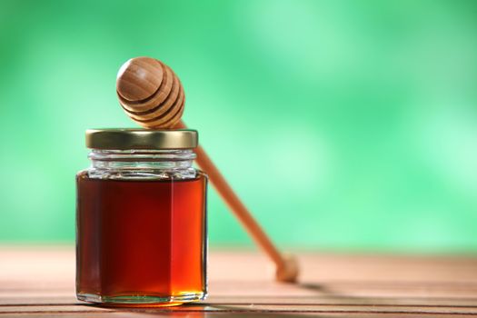 honey muddler resting on top bottle of honey