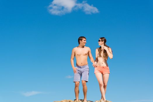 couple jumping together holding hands on a background of blue sky