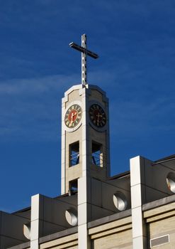 Cross and clock of modern catholic church on sky background