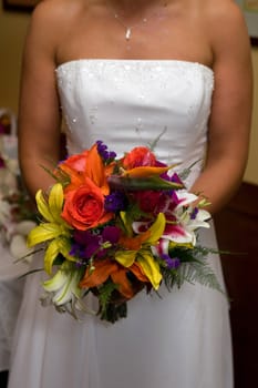A bride in a white wedding dress holds her bridal bouquet.