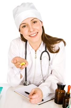 The affable young woman-doctor looks in a shot and holds in a palm some yellow tablets

