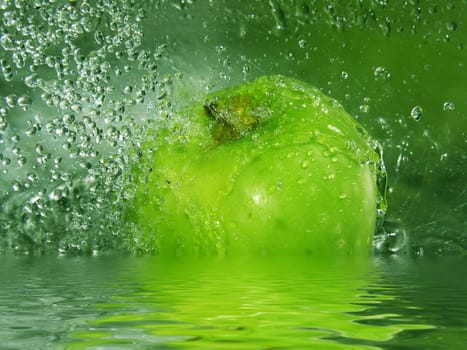 Water drops falling onto a green apple