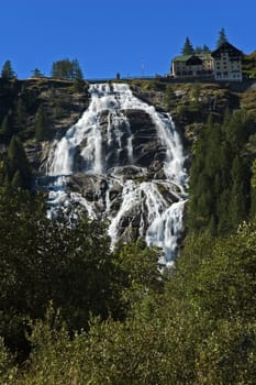 Alpine waterfall with clear blue sky and trees