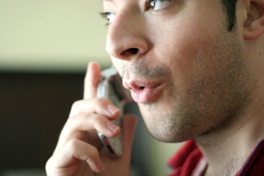 A man on his cell phone speaking excitedly or acting surprised about what he is hearing.