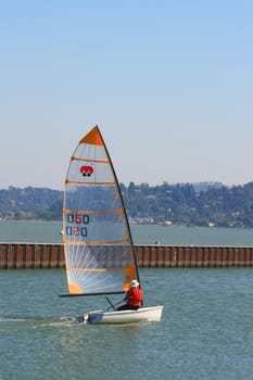 Sailor on a small boat sailing away.
