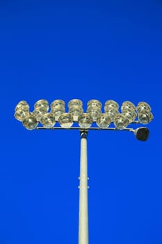 Close up of stadium lights over blue sky.
