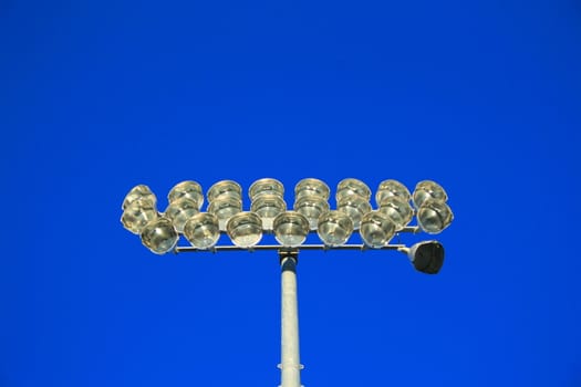 Close up of stadium lights over blue sky.
