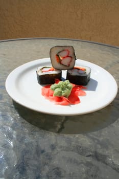 Sushi next to wasabi and sushi ginger on a platter.
