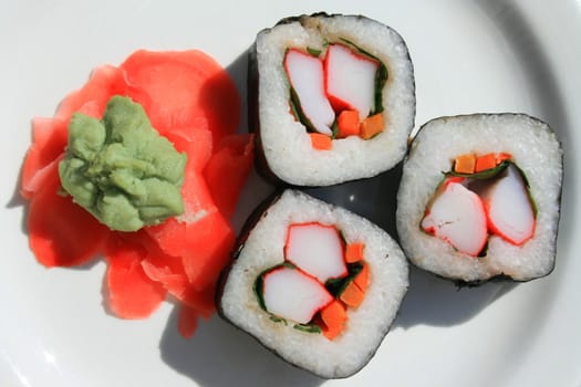 Sushi next to wasabi and sushi ginger on a platter.
