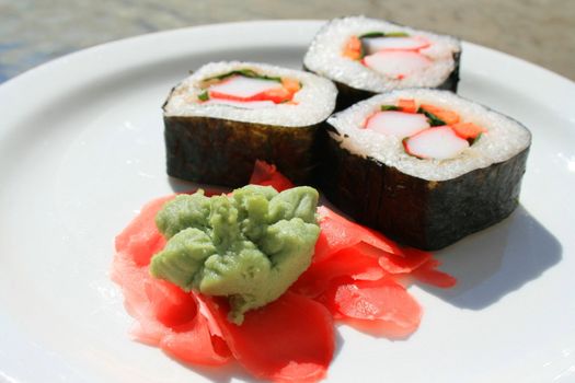 Sushi next to wasabi and sushi ginger on a platter.
